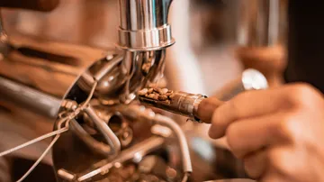 Kaffeebohnen werden in eine Maschine eingefüllt, metallisch glänzend.