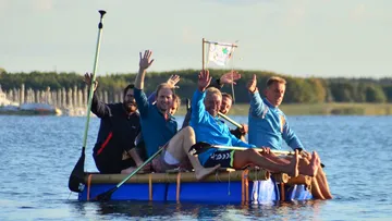 A group of men waving on a raft in the water.