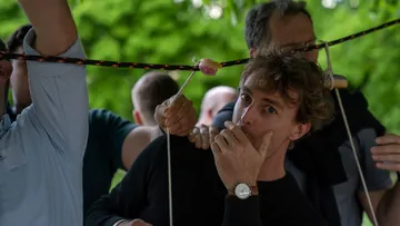 Junger Mann hält den Mund, während andere arbeiten.