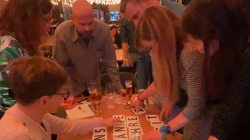 People work together at a table, arrange letters.