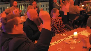 Gruppe applaudiert fröhlich in einem lebhaften Restaurant.