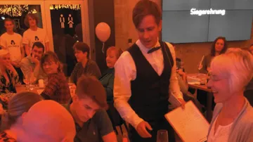 Ein Kellner serviert Bestellungen in einem geschäftigen Restaurant.