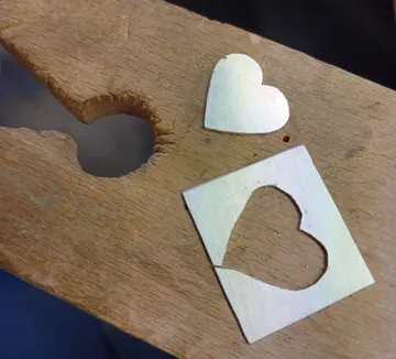 Herzchen aus Metall und Papier auf Holzplatte, bearbeitet.