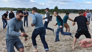 Group game on the beach, people running and laughing.