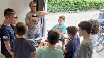 Kursleiter zeigt Kindern Werkzeug