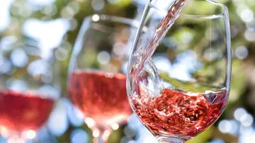 Glass is filled with pink drink, outdoors.