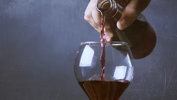 Eine Hand gießt roten Wein in ein Glas.