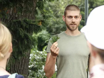 Man shows a group of plants outdoors.