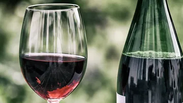 Red wine in the glass, next to the bottle, natural environment.