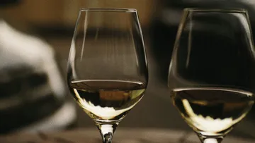 Zwei Weingläser stehen auf einem Tisch, gefüllt mit Wein.