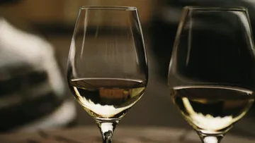 Zwei Weingläser stehen auf einem Tisch, gefüllt mit Wein.