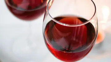 Red wine glasses reflect light on a table.