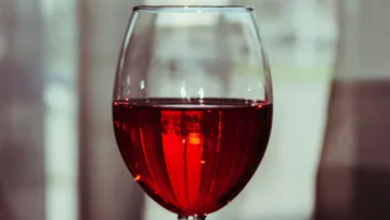 Rotwein in einem Glas steht in einem hellen Raum.