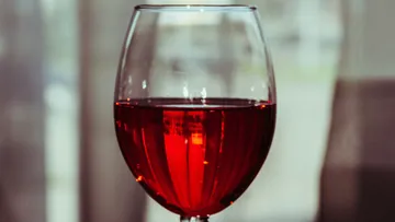 Ein Glas mit rotem Getränk steht auf einem Tisch.