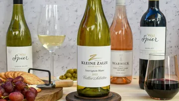 Flasche Sauvignon Blanc steht neben Weingläsern und Snacks.