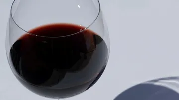 Ein Weinglas mit roten Wein steht auf einer weißen Oberfläche.