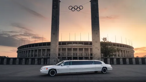 A white stretch limousine car is parked in front of the Olympic Stadium.