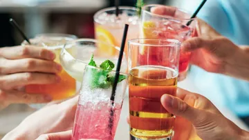 Six drinks are toasted at a celebratory moment.