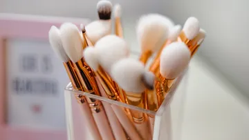 Brushes are placed on a table in a transparent container.