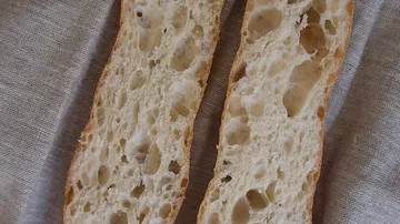 Two slices of bread lie on a fabric surface.