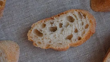 A slice of bread is lying on a grey cloth, viewed.
