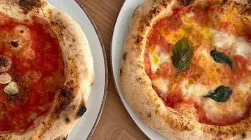 Two pizzas on plates, one with tomato sauce, one with cheese.