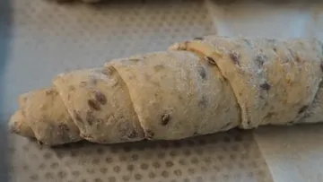 A piece of dough is rolled on baking paper.