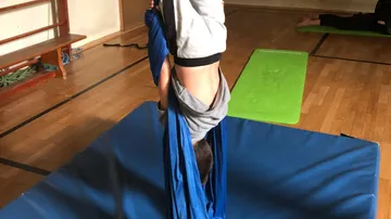 Ein Kind hängt kopfüber in einem blauen Tuch.