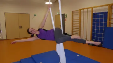 Frau schwingt an Tüchern in einem sportlichen Raum.