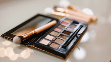 Eine Make-up-Palette liegt mit Pinseln auf einem Tisch.