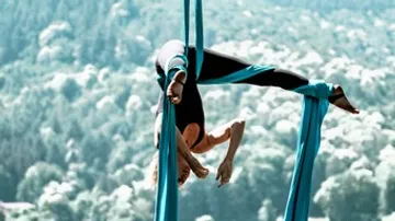 Accrobatine hangs over the landscape in blue cloths.