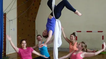 Eine Frau hängt kopfüber an Tüchern, andere applaudieren.