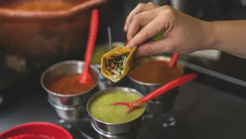 Taco is lifted to dip into sauces.
