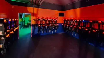 Laser tag equipment hangs on walls in dark rooms.