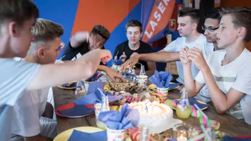 Friends celebrate together with food and cake at the table.