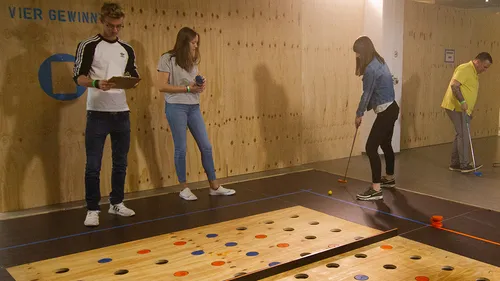 People playing a mini-golf type game indoors.