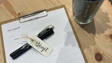 Pen and paper lie on a wooden surface.