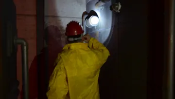 A person in a yellow suit stands in front of a light.