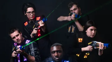 Five people play with laser toys in a dark room.