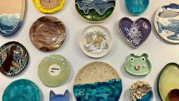 Colourful plates hang on a wall, showing various motifs.