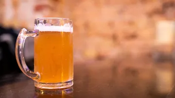 A beer glass is on a table in a bar.