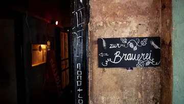 Brewery sign on a rough wall in a corridor.