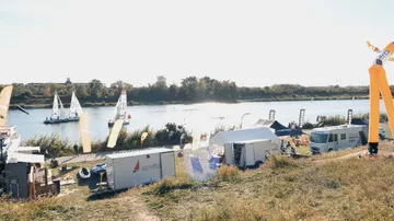 Boats sail on water surrounded by festival stands.