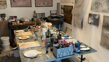 A messy table with painting supplies in a studio.