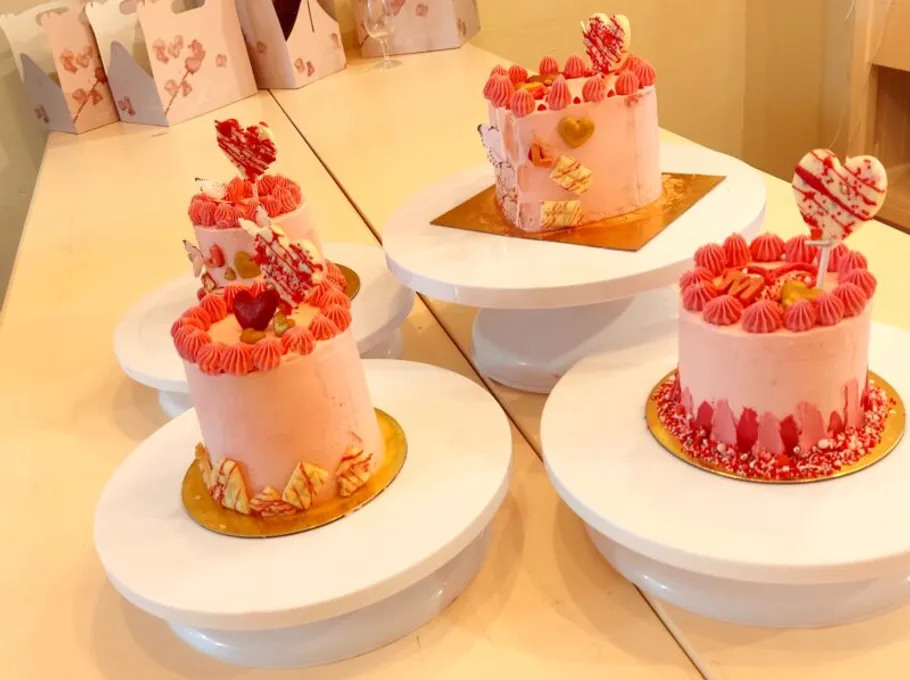 Fünf rosa Kuchen stehen dekorativ auf weißen Ständern.