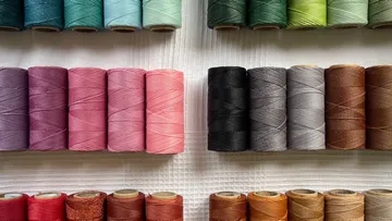 Colored spools of thread are neatly arranged on fabric.