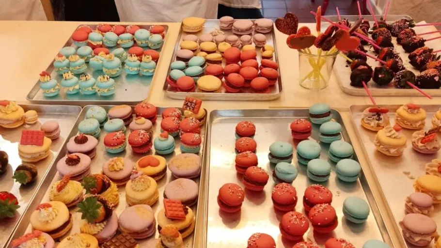 Verschiedene bunte Macarons und Desserts auf Tabletts.