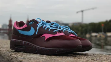 Sports shoes stand on the banks of a body of water.