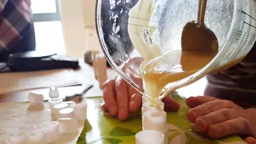 Liquid is poured into molds from a measuring cup.