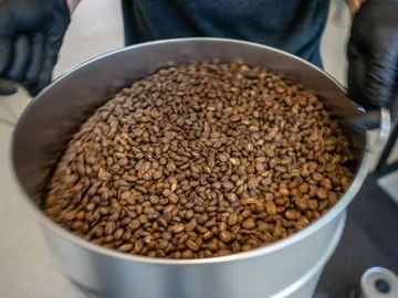 Coffee beans in a container are stirred, industrial environment.